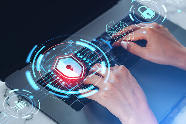 Digital cybersecurity icons overlay hands typing on a laptop keyboard.