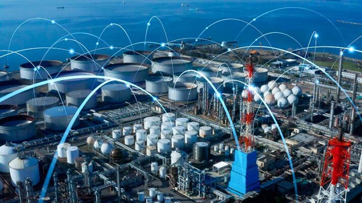 Industrial complex near water with numerous storage tanks and chimneys. Blue arcs overlay, symbolizing connectivity and technology integration powered by private 5G.