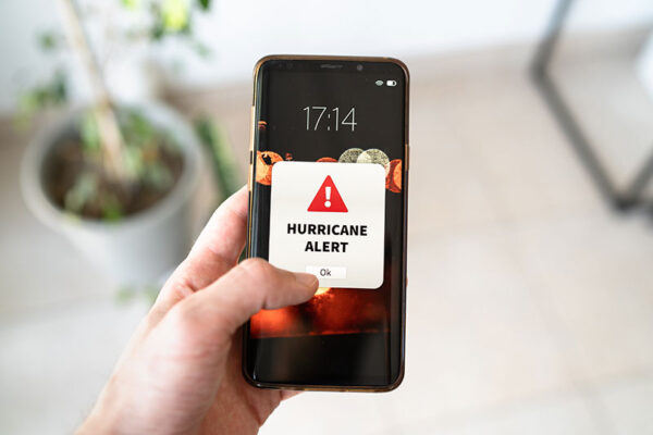 A smartphone showcases a "Hurricane Alert" notification, showing how smart utilities send emergency alerts to users.