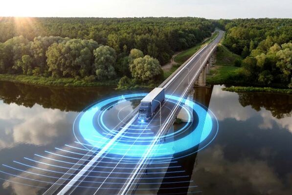 A truck crosses a bridge over a forested river, overlaid with blue signal lines and concentric circles. The scene suggests advanced technology or autonomous driving systems.