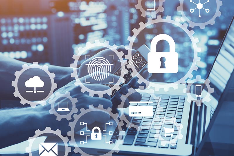 Hands typing on a laptop keyboard with digital security icons, including a lock and a fingerprint, superimposed over the image, emphasizing IoT cybersecurity.