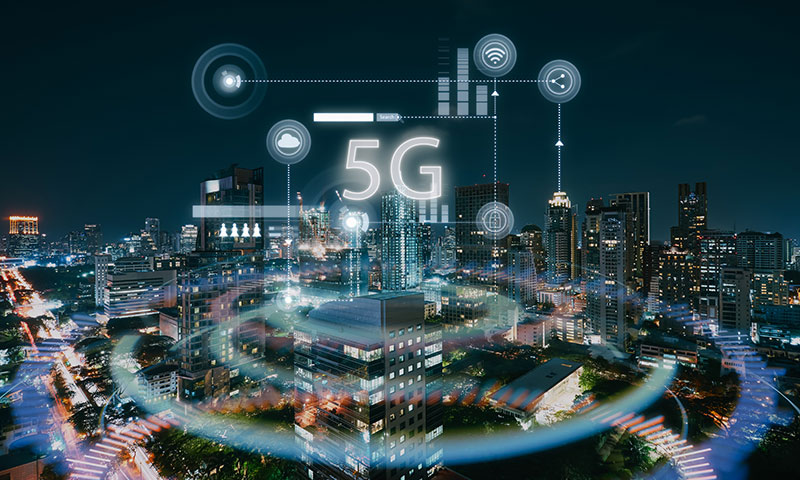 A city skyline at night is overlaid with digital technology graphics and a prominent "5G" symbol, illustrating that 5G technology defines advanced communication.