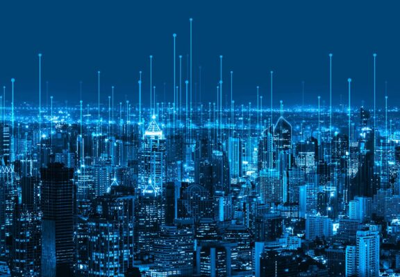 An image of a smart city at night, overlaid with lines pointing upward to represent connectivity.
