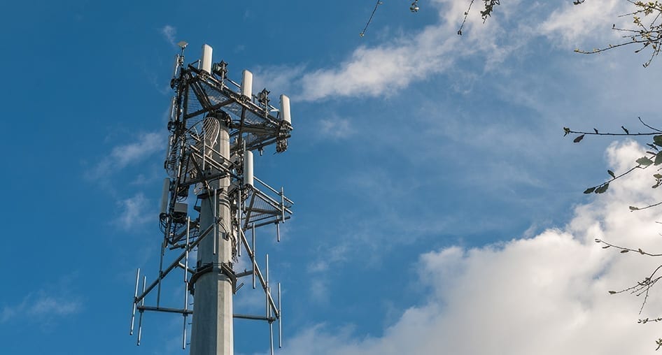 Cellular tower against a partly cloudy sky. 4 x 4 MIMO means having four antennas on the device side and four antennas on the cellular tower side.