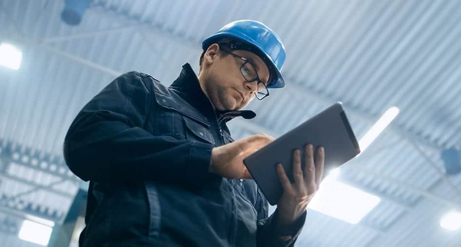 Person in a hard hat looking at data on a tablet.