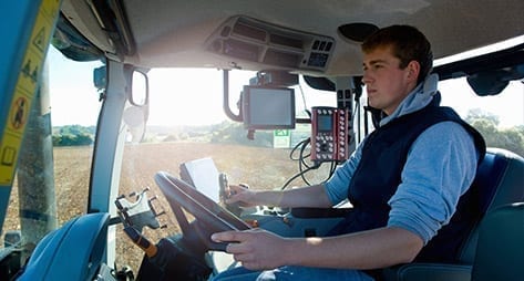 Cabin view of person driving tractor in a field.