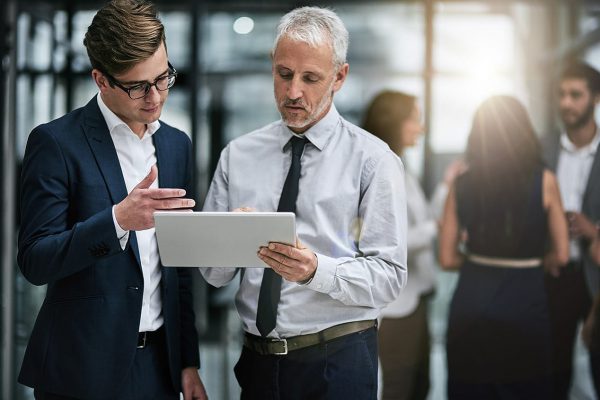 Two people going over data on a tablet.