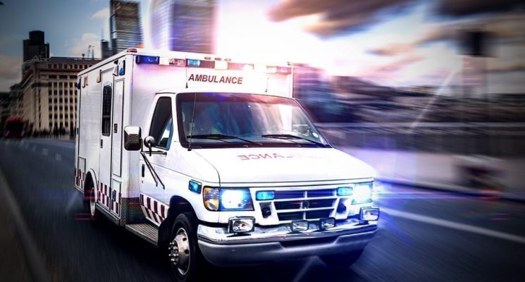 An ambulance with its lights on speeding down the highway in a city.