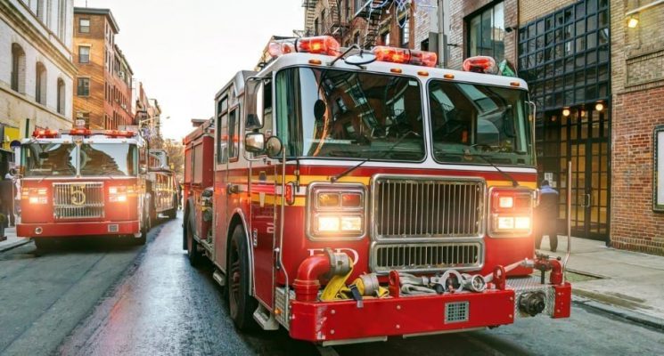 Two fire trucks driving down a city street