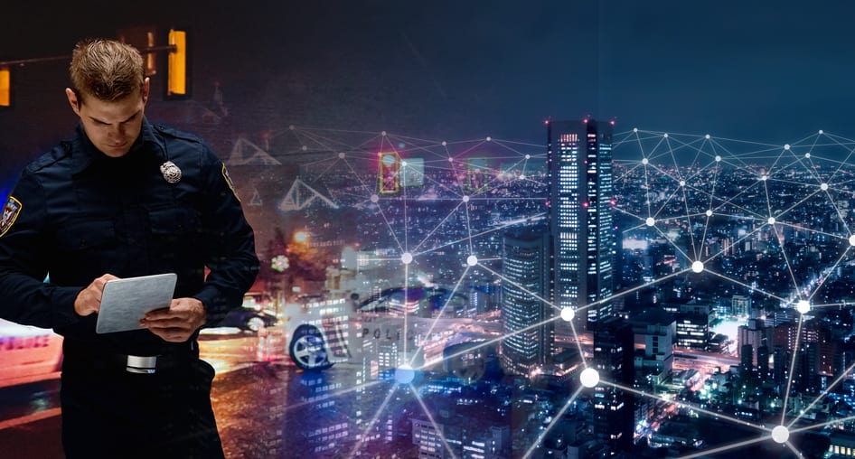 Merged image of a first responder adding information to a tablet next to an aerial view of a city at night with a network of connected dots.