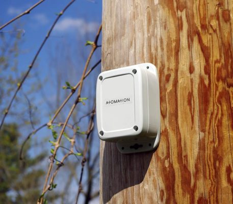 A white device is attached to a wooden pole.