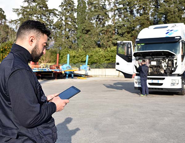 A man looking at a tablet in front of a truck.