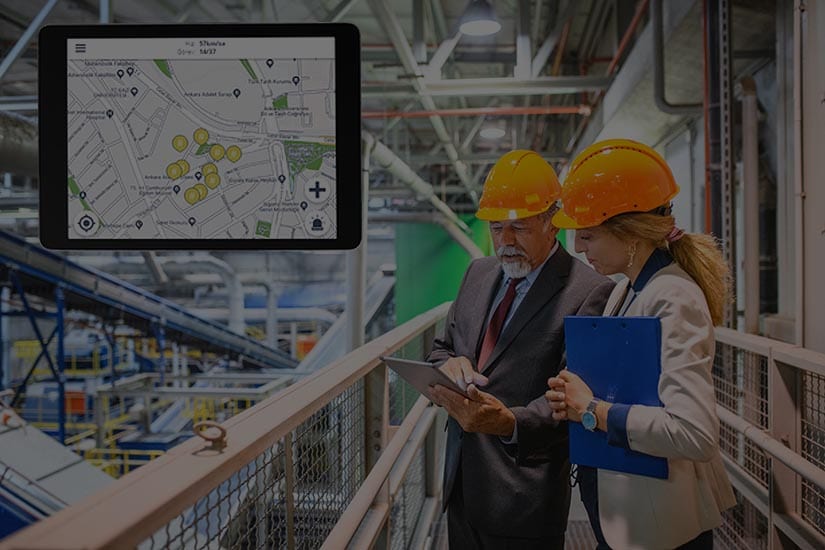 Two people in hard hats looking at a map on a tablet.