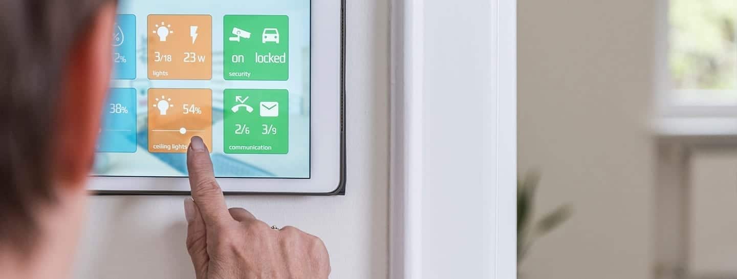 A person is pointing at an iPad on the wall in a home automation setup.