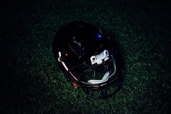 A football helmet sitting on the grass at night.