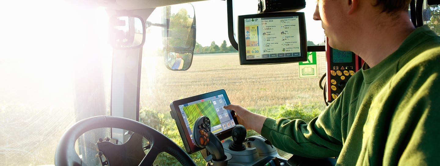 A man in a green shirt is using a tablet for precision farming in a tractor.