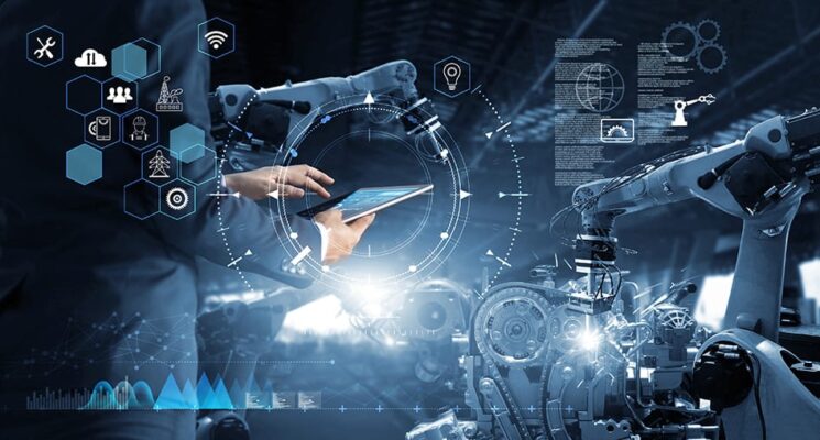 Image of person in a business suit in a factory, viewing data from robotic arms on a tablet. Image is overlaid with data graphics and icons for IIoT industries, smart manufacturing and Industry 4.0.