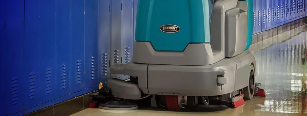 A floor scrubber in a hallway with blue lockers.