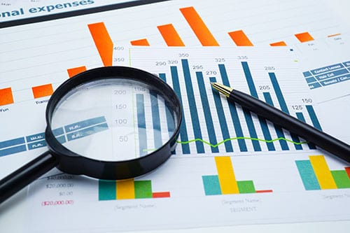 A magnifying glass and graphs on top of a table in an IoT monitoring setup for remote crop and cattle tracking.