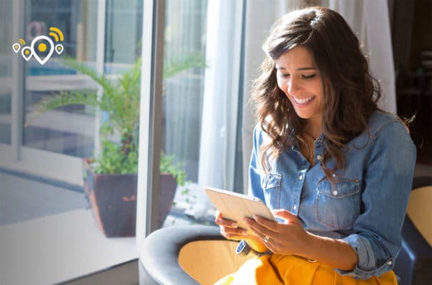 A woman sitting in a chair looking at a tablet.