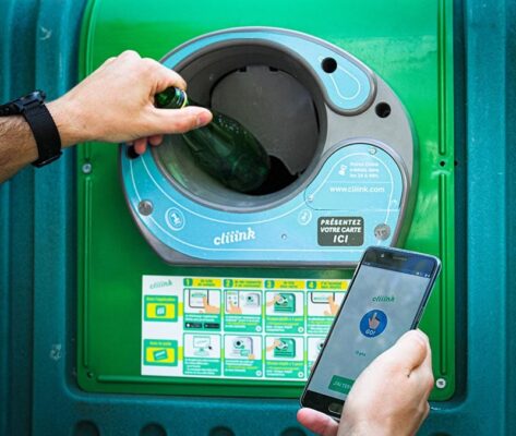 A person using a smart phone to open a bottle in a recycling machine.