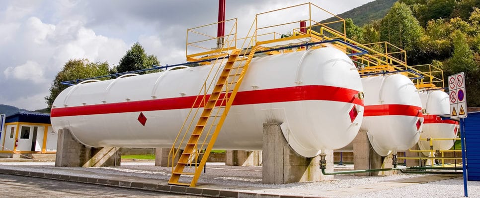 A group of large white and red tanks in front of a building.