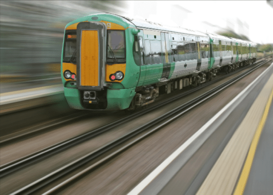 A green and yellow train on the tracks.