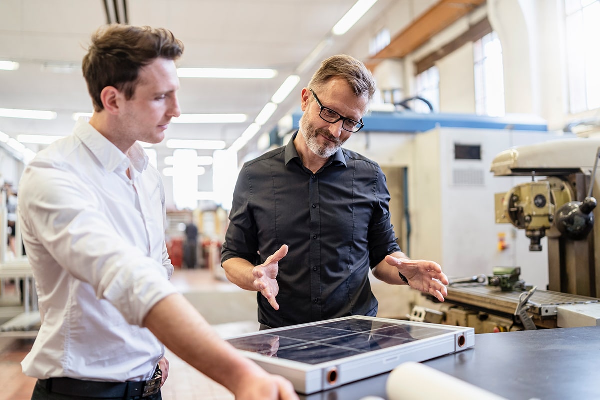 Two men inspecting a solar panel in a smart manufacturing facility.