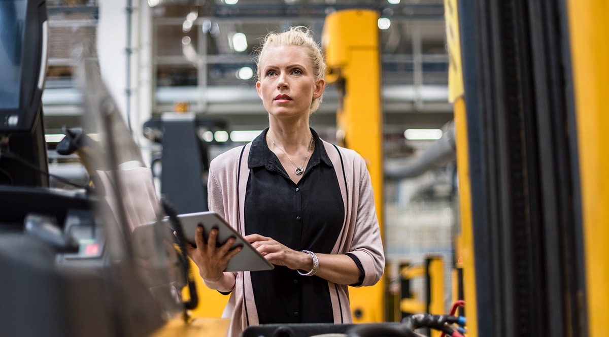 A woman standing in front of a forklift in a smart manufacturing factory.