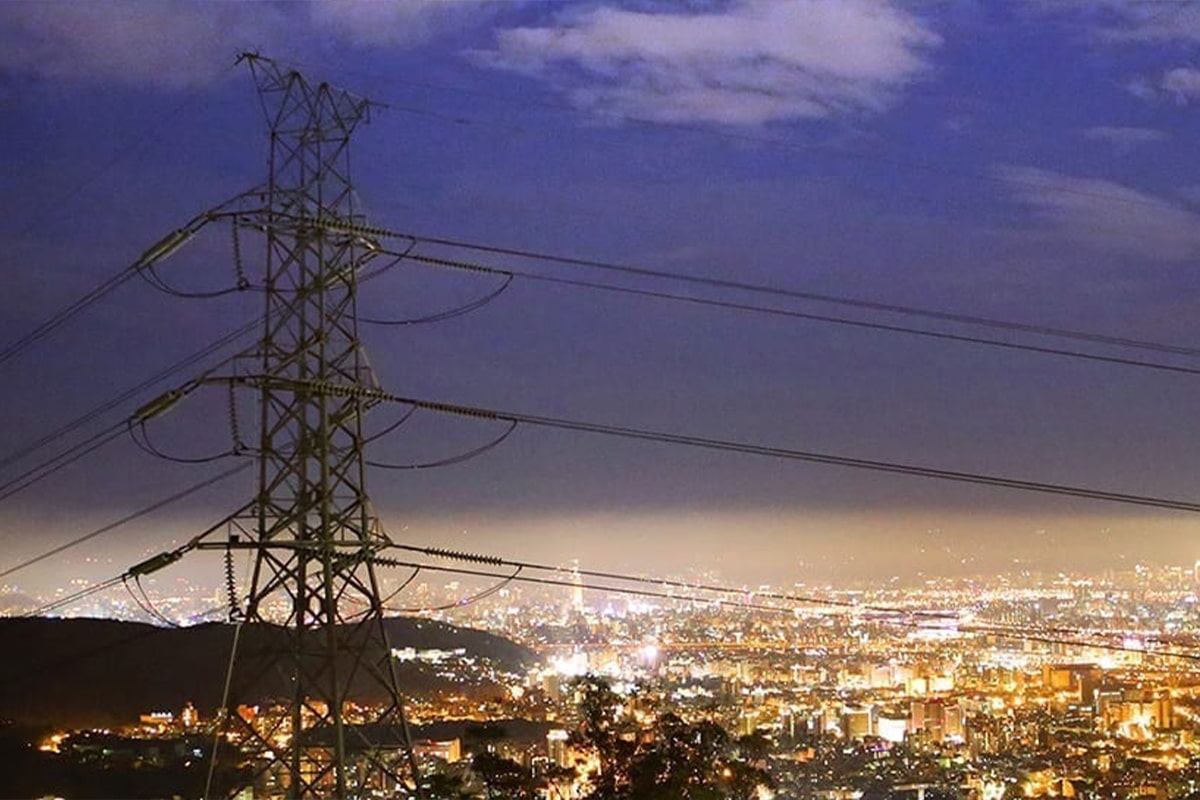 A view of a city at night with electricity pylons showcasing a modern smart grid system.