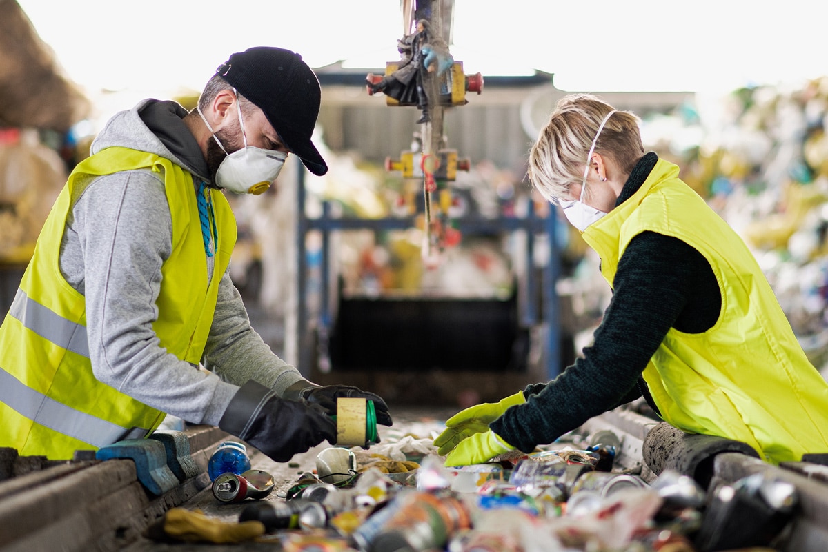 Two people working at a recycling plant, using smart waste management techniques.
