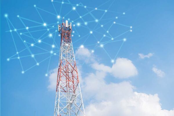 A telecommunications tower stands against a blue sky with clouds, overlaid with a digital network graphic symbolizing wireless connectivity.