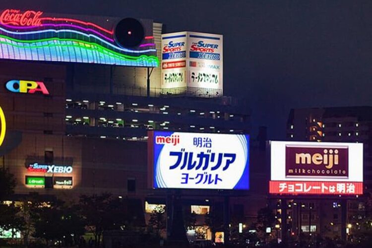 A group of smart digital billboards in a city at night.
