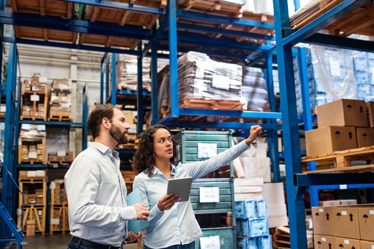 Two people in a warehouse inspecting shelves for supply chain management.