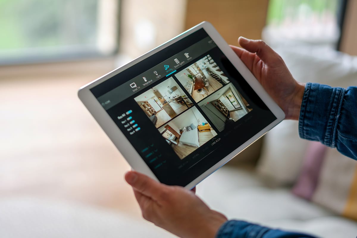 A person holding an iPad displaying images of a smart security camera.