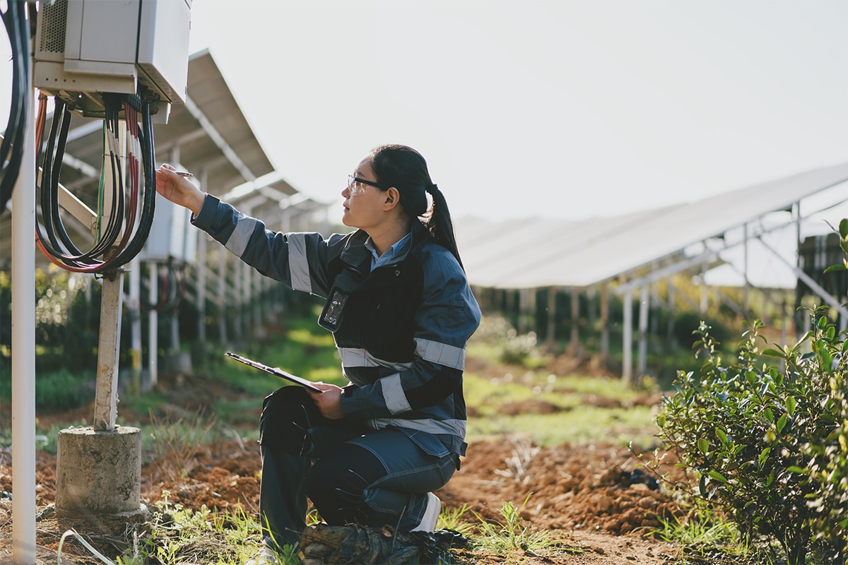 A woman inspecting a solar panel in a field.