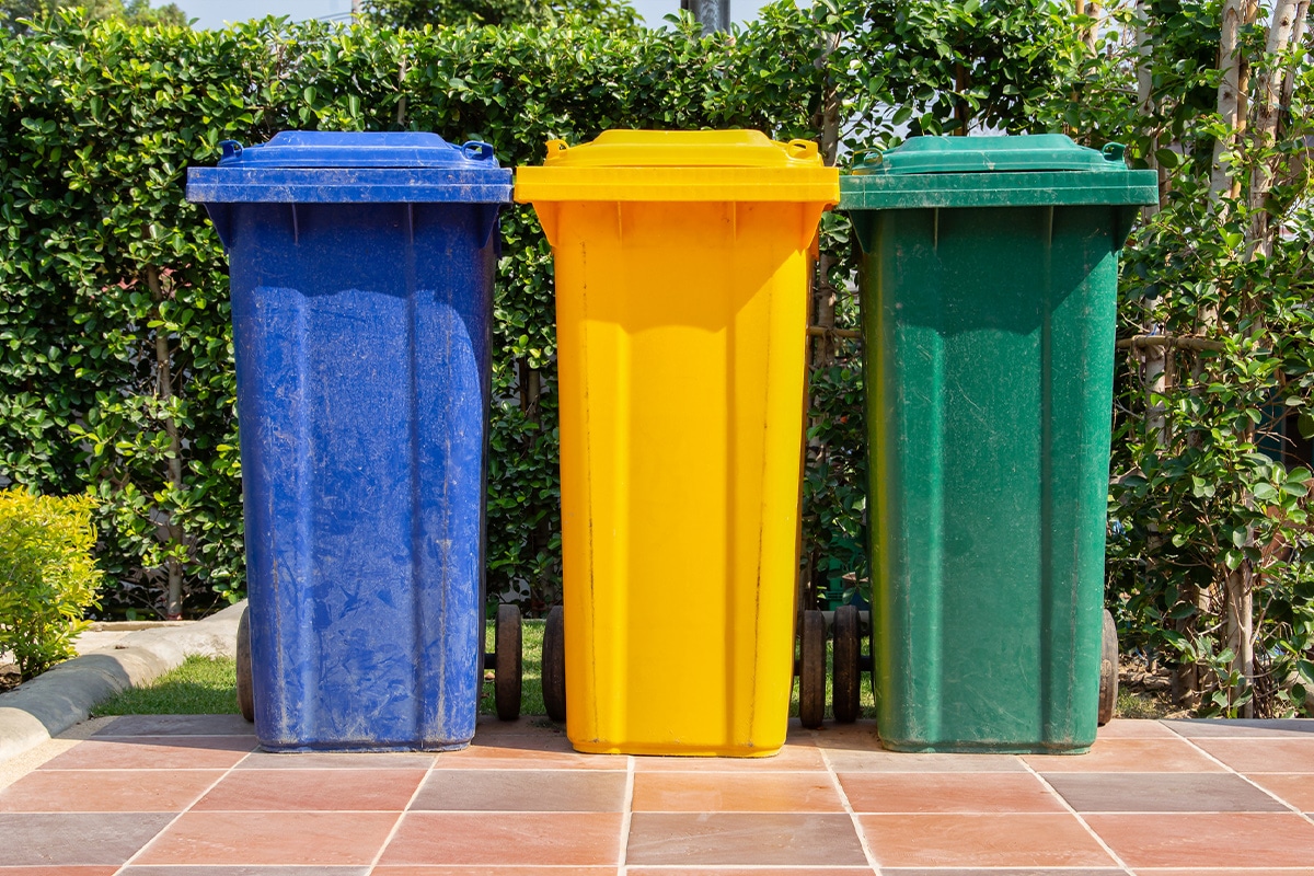Three colorful trash cans are aligned on a tiled floor, showcasing smart waste management.