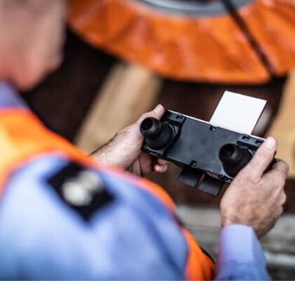 A man in an orange vest is holding a camera.