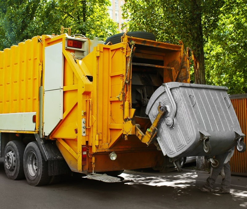 An IoT-connected garbage truck is parked on the street.