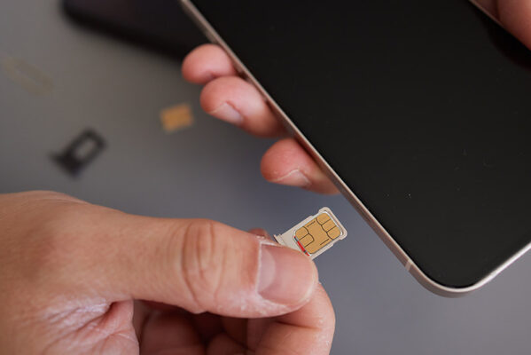 A person is inserting a SIM card into a smartphone.