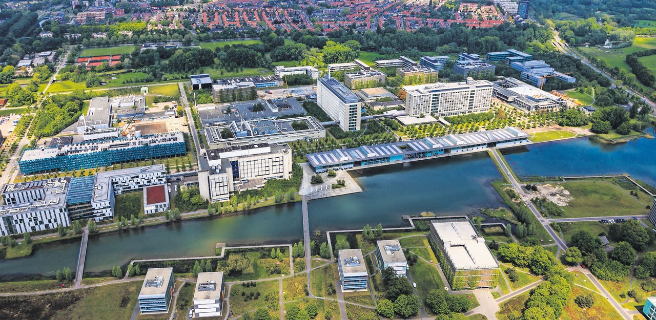 An aerial view of a campus near a river with an antenna.