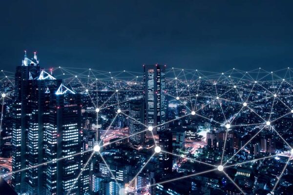 A network of glowing lines and dots that represent a connected smart grid overlay an illuminated nighttime cityscape.