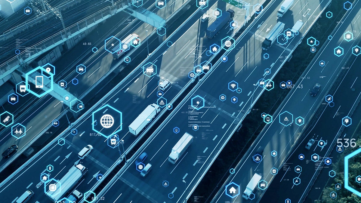 Aerial view of a highway with trucks driving on it, overlaid with connectivity icons for telematics and asset tracking.