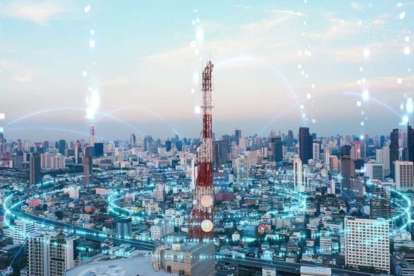 A telecommunications tower in the middle of a cityscape with overlaid digital network graphics circling the tower.