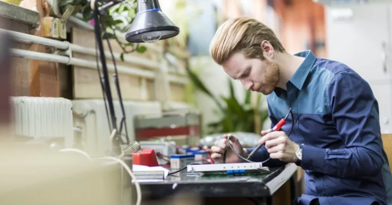 An engineer soldering components to an IoT device. 