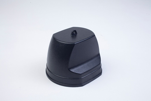 A black, dome-shaped plastic cover with a small loop on top sits on a plain white surface.
