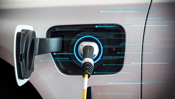 An electric car is plugged into a charging station, facing EV charging challenges due to poor connectivity.