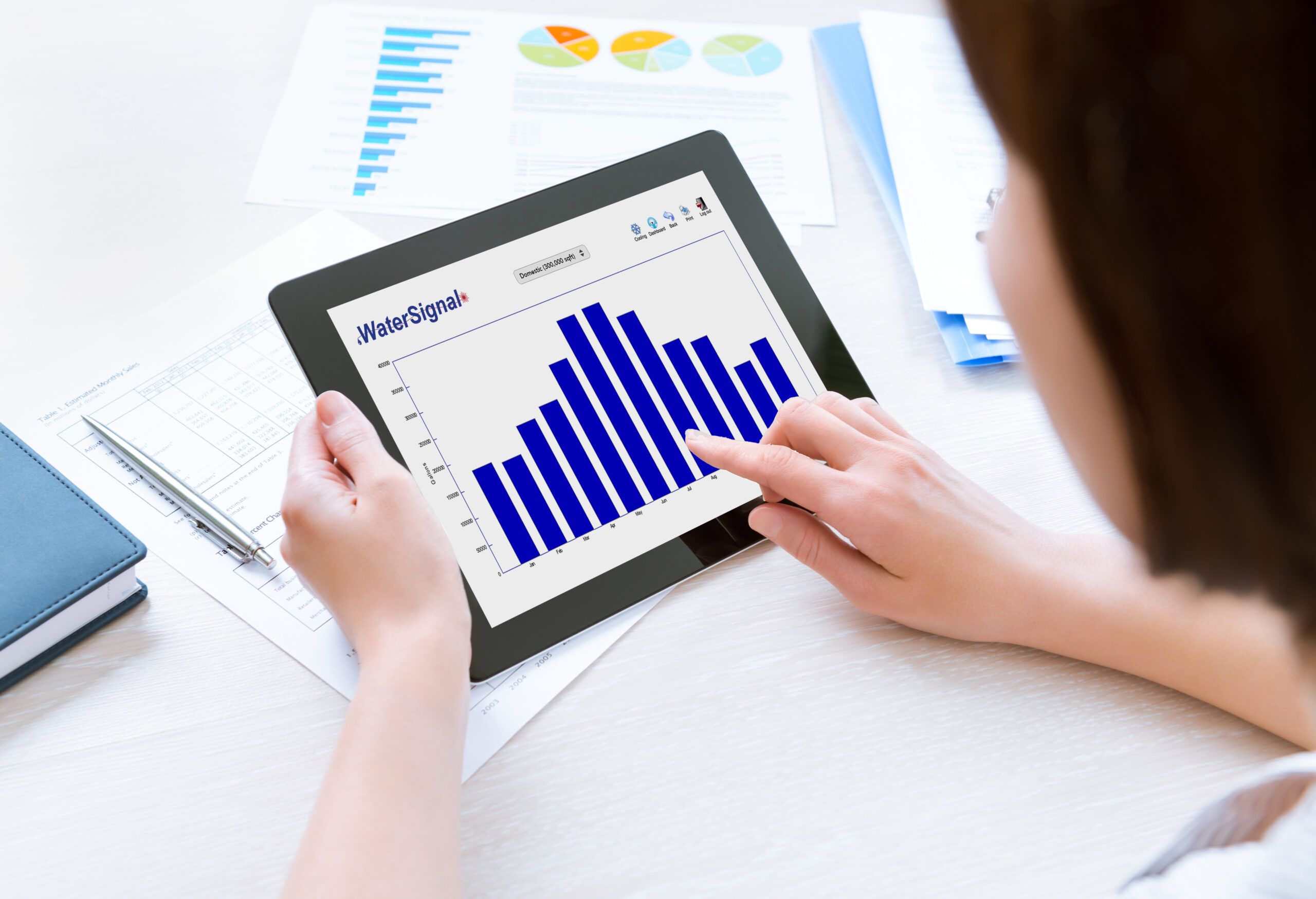 A woman is utilizing a tablet with a graph representing IoT utilities.