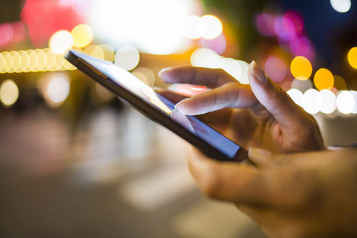 A person using an IoT device in a city at night.