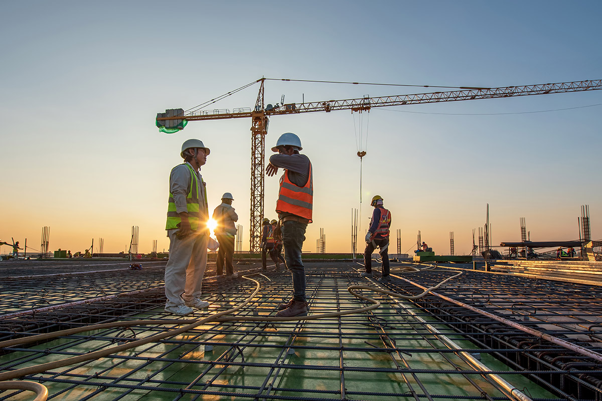 Construction workers on an IoT construction site at sunset.